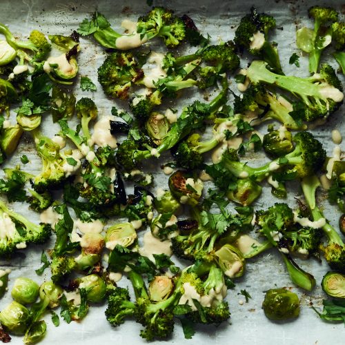 This is a photo of roasted broccoli and Brussels sprouts with tahini lemon drizzle. These veggies are all good for cancer prevention.